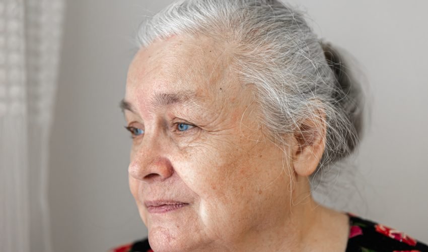 Close up portrait of elderly woman looking out the window.