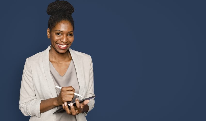 Smiling woman writing notes on tablet digital device