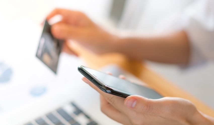 Hands holding a credit card using laptop computer and mobile pho
