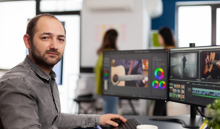 Videographer looking at camera smiling working in creative startup workplace