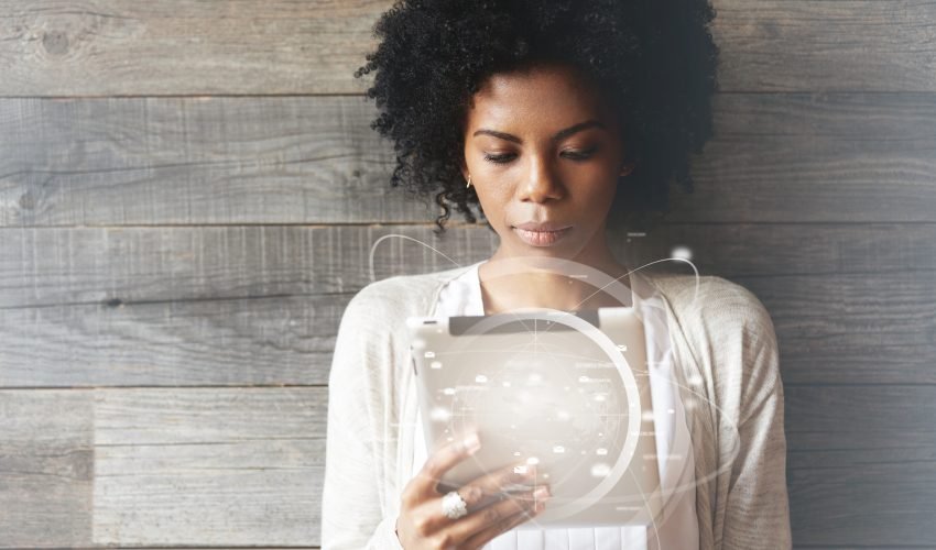 Futuristic technology and communication. Beautiful smiling black girl with Afro hairstyle using digital tablet pc or touch pad, checking email or typing message. Worldwide connection interface