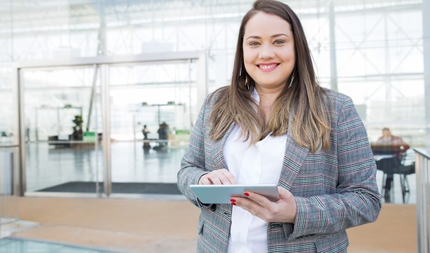 Positive lady with tablet posing in business center