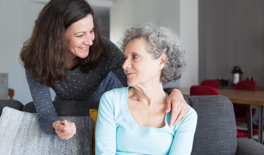 Smiling adult daughter supporting sad senior mother