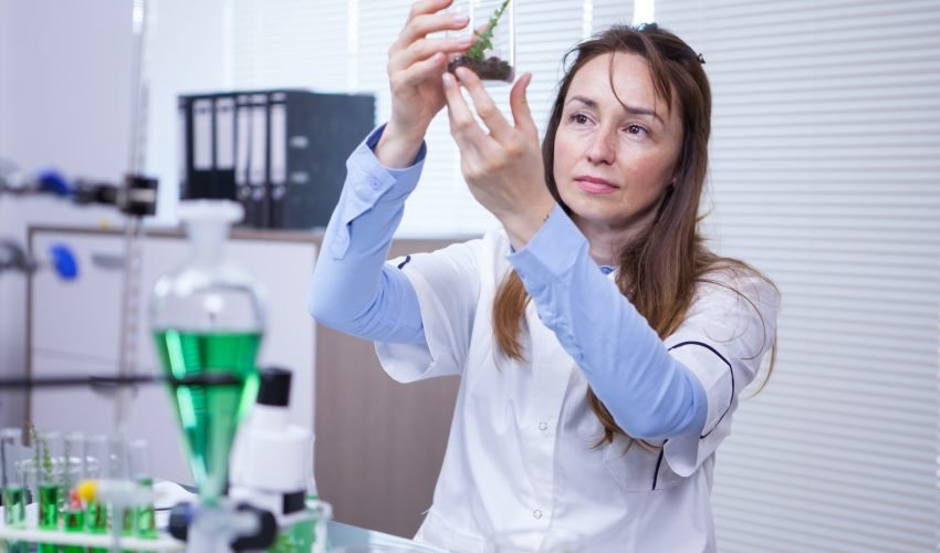Female scientist holding up a sample of soil in a agriculture research lab