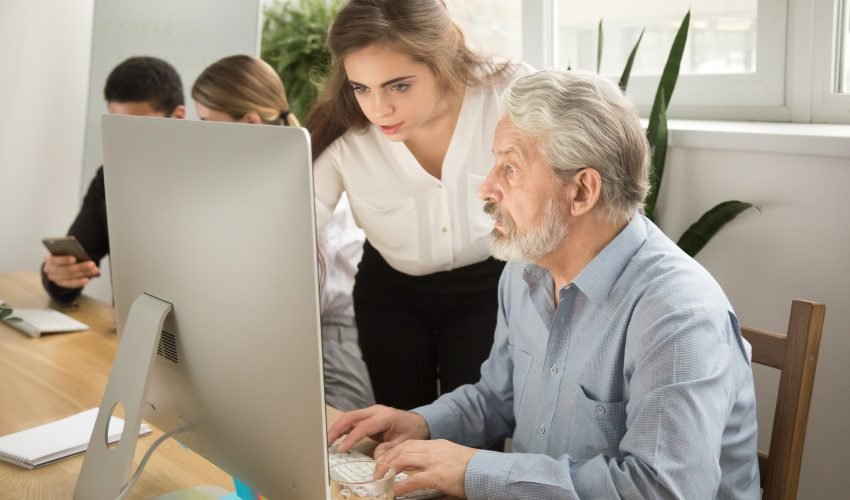 Female executive teaching senior office worker helping explainin