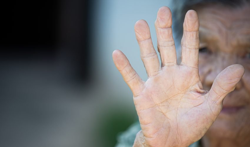 close up picture of old woman’s hand showing anti symbol