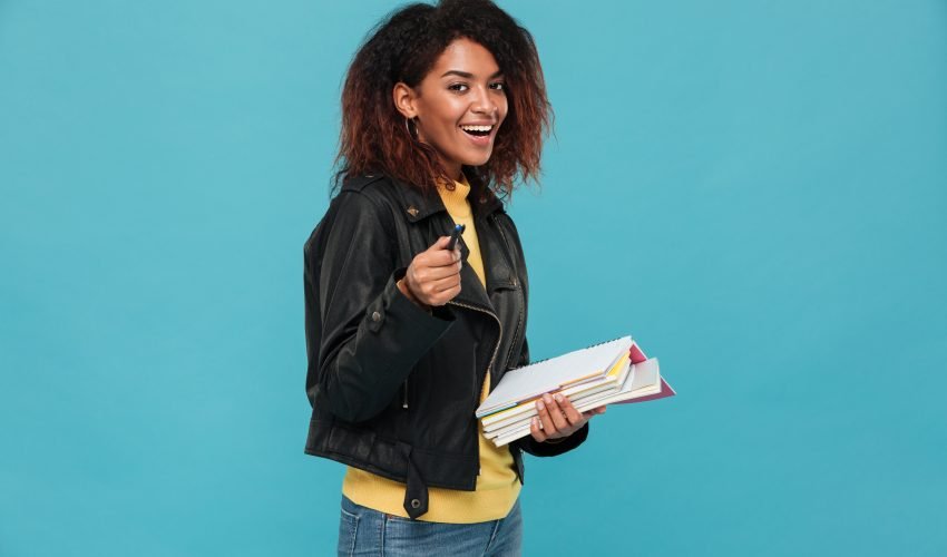 Young cheerful african woman writing notes pointing to you.