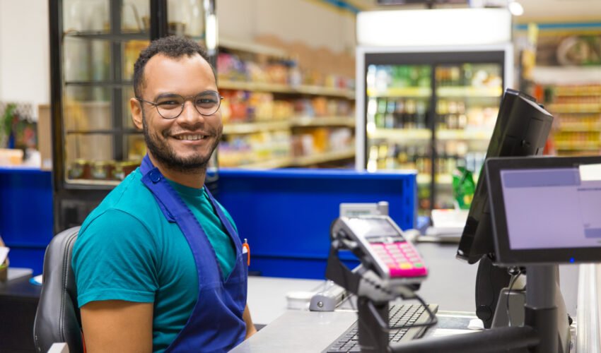 Smiling African American cashier sitting at checkout